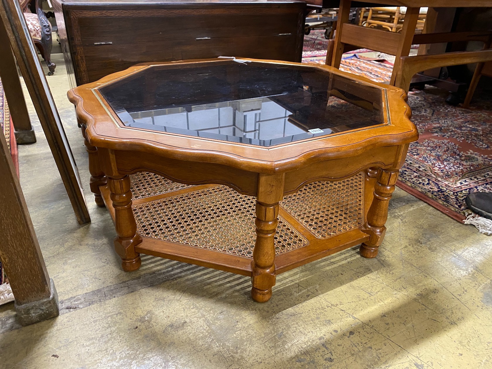 A modern octagonal brass mounted walnut glass top coffee table with caned undertier, diameter 100cm, height 40cm.